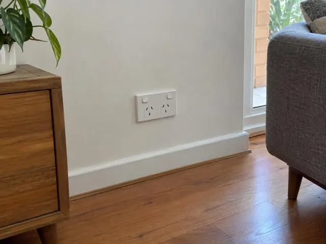 White double power point on a painted wall above skirting in a timber-floored living room in Dee Why