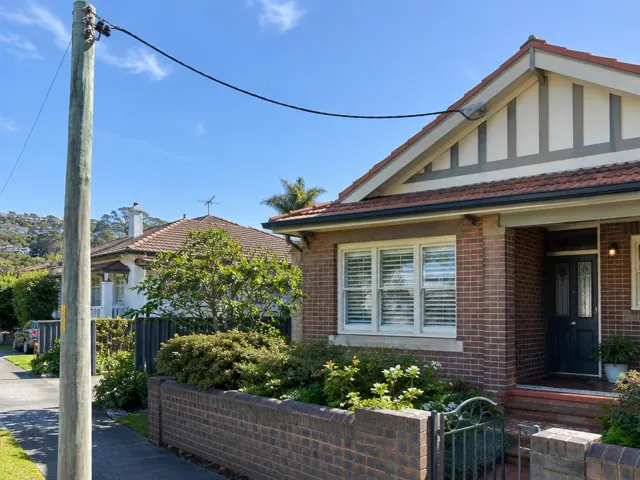 Brick house with overhead service cable and point-of-attachment bracket on the gable in Fairlight